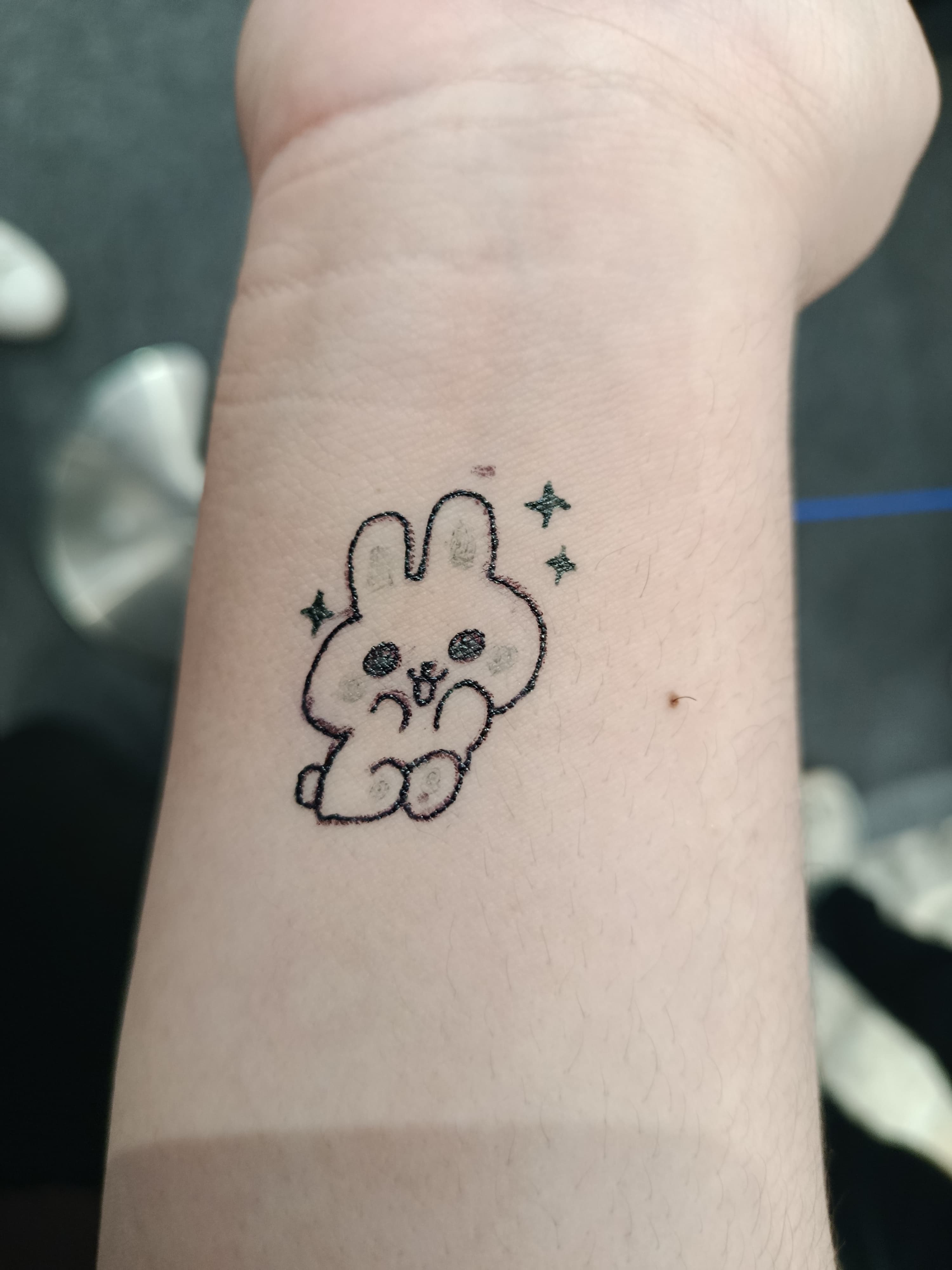 Small cartoon bunny tattoo with stars on an inner wrist