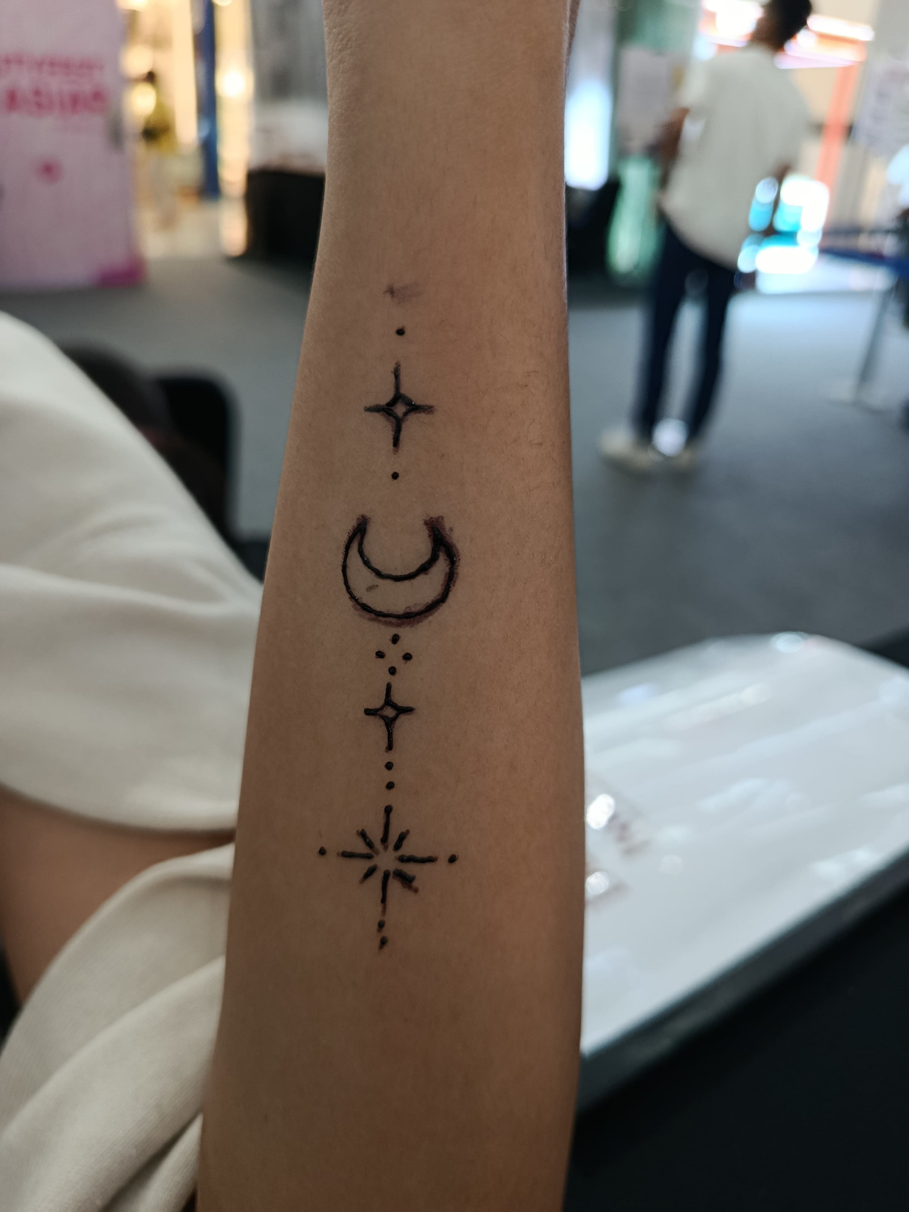 Crescent moon and star tattoos arranged along an inner forearm