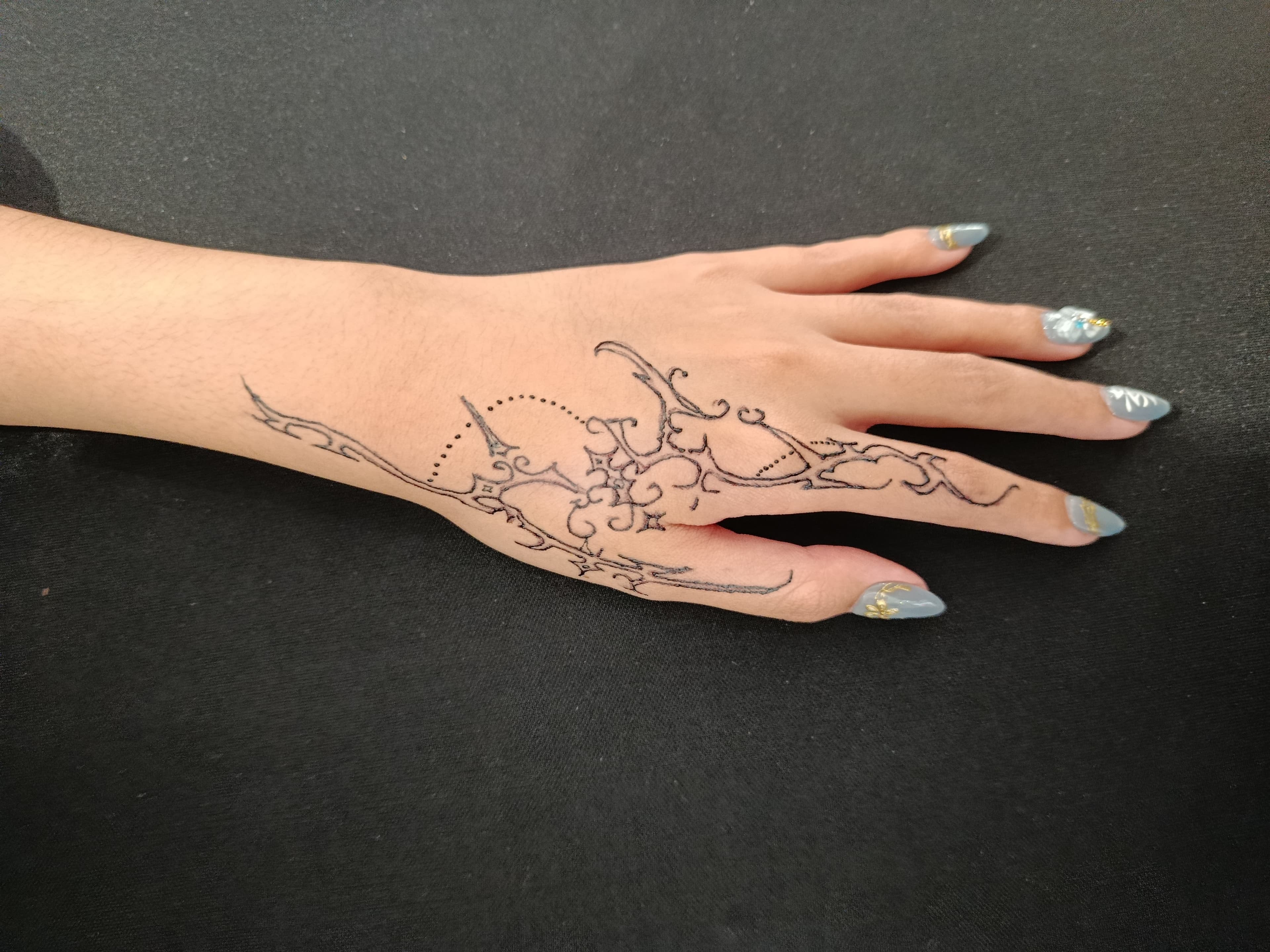 Fine-line floral tattoo across the back of a hand