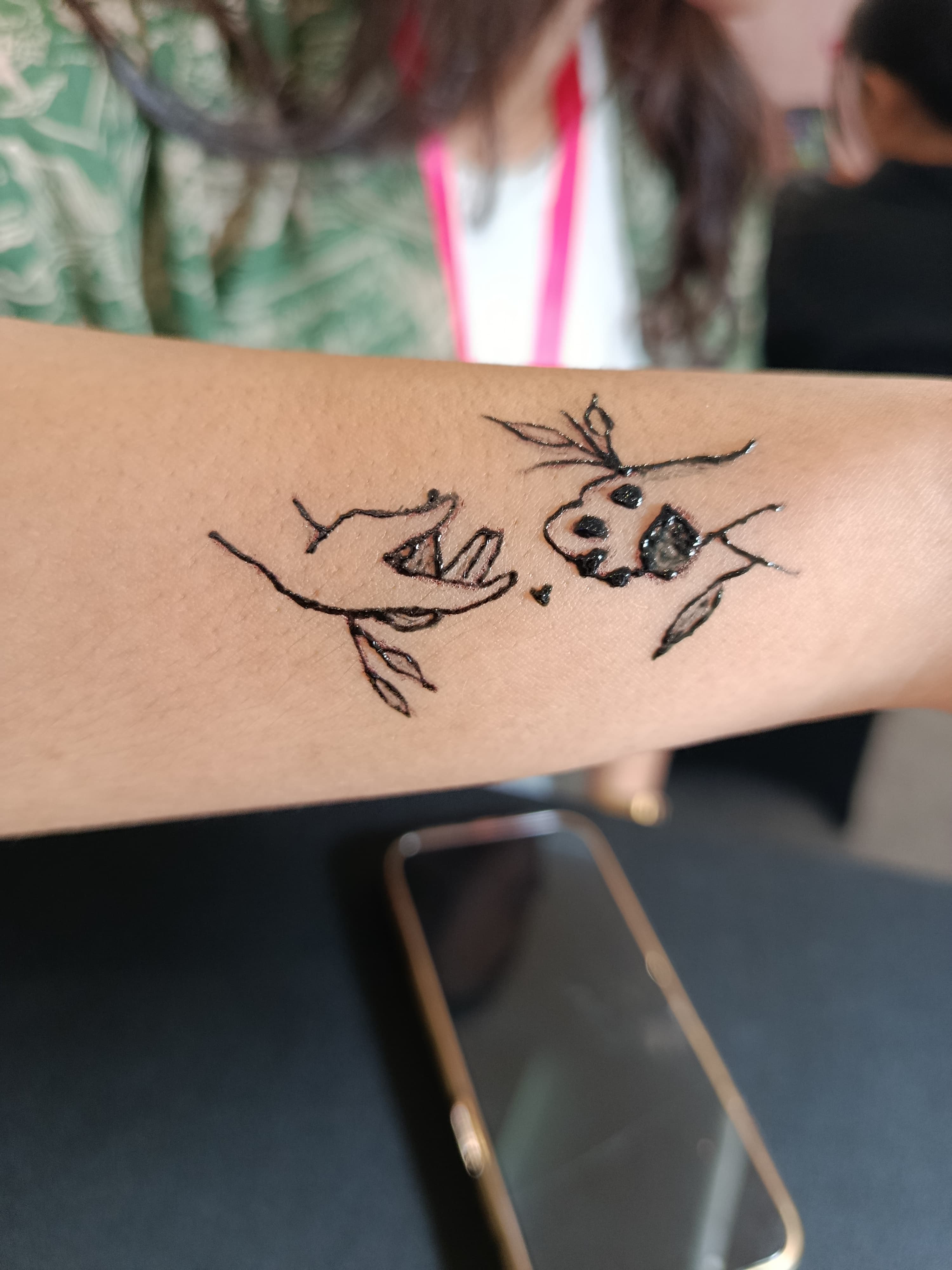 Illustrative black line tattoo of hands and botanical details on an arm
