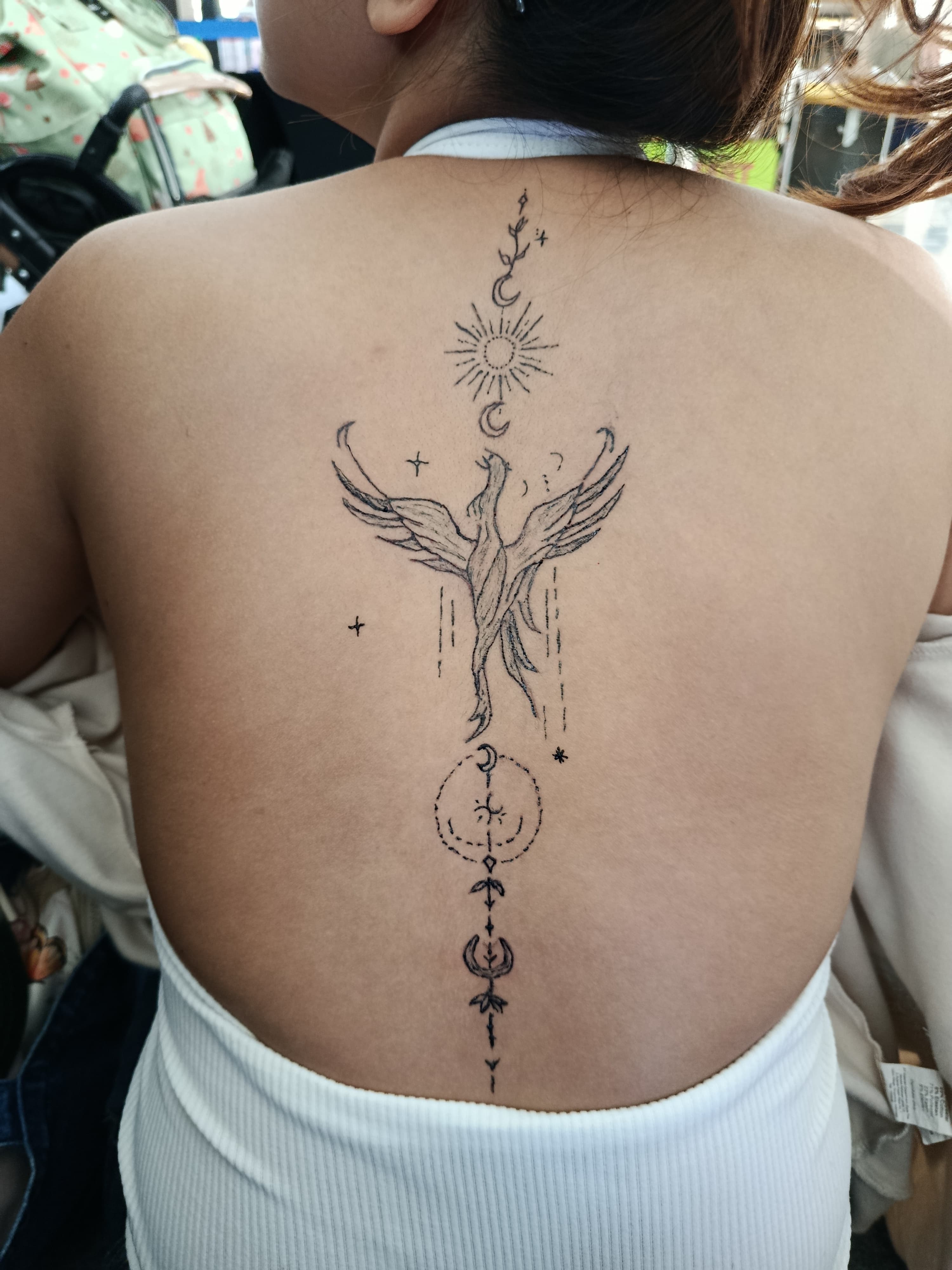 Large winged ornamental tattoo down the center of a back