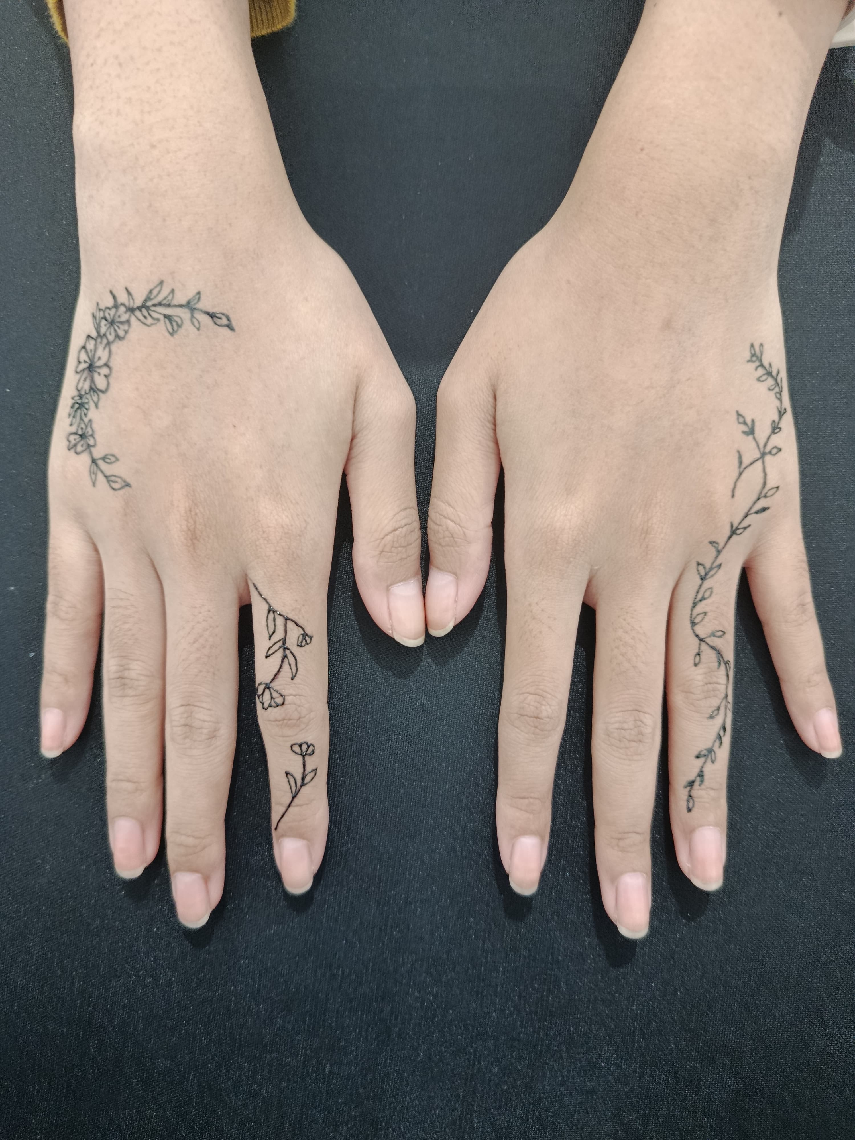 Fine botanical tattoos across two hands and fingers
